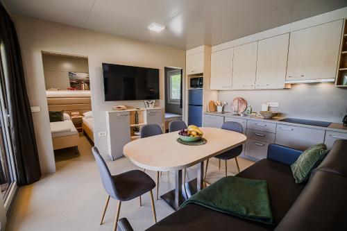 eine Küche und ein Wohnzimmer mit einem Tisch und einem Sofa in der Unterkunft DELUXE Lake View Mobile Homes with Thermal Riviera Tickets in Čatež ob Savi