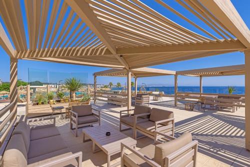 a patio with tables and chairs and the ocean at KRESTEN ROYAL Euphoria Resort in Kallithea Rhodes
