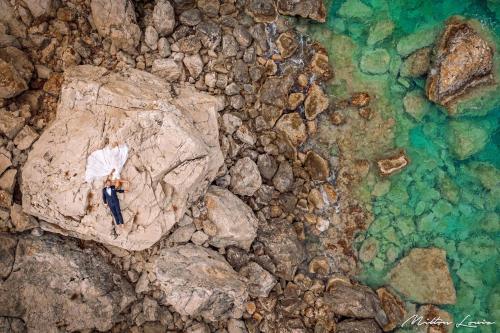 a man sitting on a rock next to the water at KRESTEN ROYAL Euphoria Resort in Kallithea Rhodes
