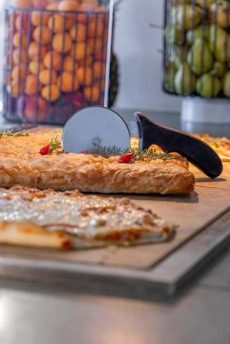 a pizza on a cutting board with a pizza cutter at KRESTEN ROYAL Euphoria Resort in Kallithea Rhodes