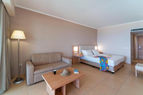 a hotel room with a bed and a couch at KRESTEN ROYAL Euphoria Resort in Kallithea Rhodes