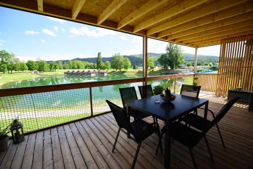a table and chairs on a deck with a view of a lake at DELUXE Lake View Mobile Homes with Thermal Riviera Tickets in Čatež ob Savi