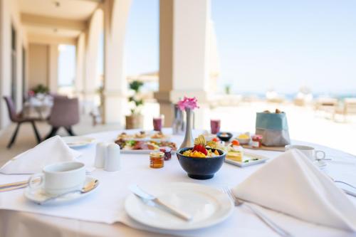 a table with plates of food and a bowl of fruit at KRESTEN ROYAL Euphoria Resort in Kallithea Rhodes