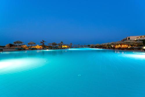 a large pool of blue water at night at KRESTEN ROYAL Euphoria Resort in Kallithea Rhodes