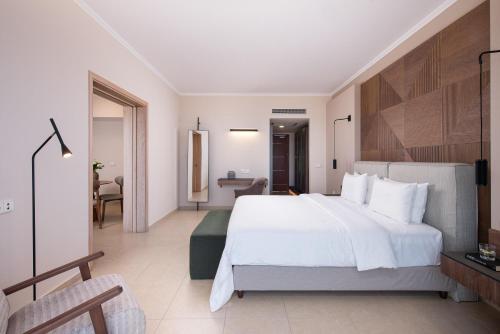 a bedroom with a large white bed and a desk at KRESTEN ROYAL Euphoria Resort in Kallithea Rhodes