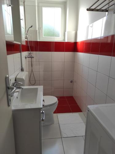 a bathroom with a toilet and a red and white wall at Apartment Elena in Dramalj