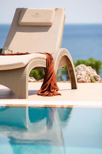 a chair with a blanket sitting next to a swimming pool at KRESTEN ROYAL Euphoria Resort in Kallithea Rhodes