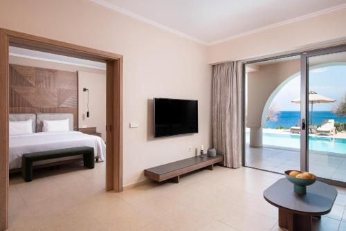 a bedroom with a bed and a tv and a balcony at KRESTEN ROYAL Euphoria Resort in Kallithea Rhodes