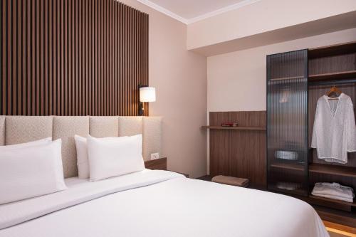 a bedroom with a white bed and a wardrobe at KRESTEN ROYAL Euphoria Resort in Kallithea Rhodes
