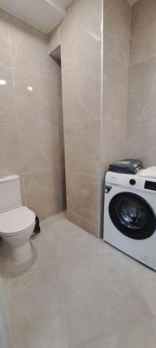 a bathroom with a washing machine and a toilet at Apartamentai Mažvydo alėjoje in Klaipėda