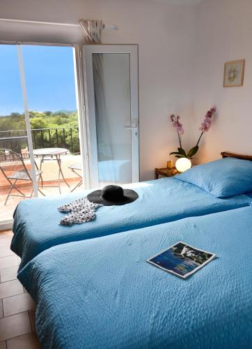 - une chambre avec 2 lits avec des draps bleus et une fenêtre dans l'établissement Appartement avec piscine cozy spacieux, climatise, vue mer! Plages et centre 15 mns!, à Cavalaire-sur-Mer