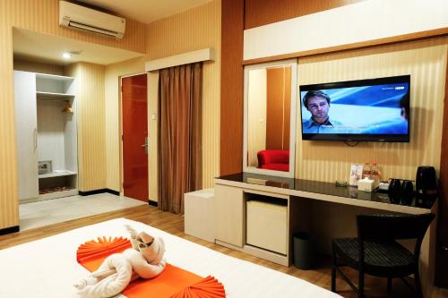 una sala de estar con TV y una habitación con cama en Halogen Hotel Airport Surabaya, en Sidoarjo