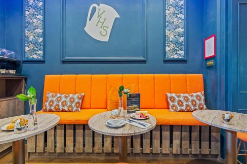 ロンドンにあるバンクーバー スタジオの二つのテーブルがあるレストランのオレンジのベンチ
