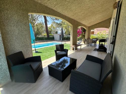 une terrasse avec des chaises, une table et une piscine dans l'établissement Stella Marina - Maison climatisée avec piscine et accès direct à la plage, à Borgo