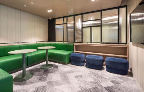a waiting room with green seats and tables and windows at Holiday Inn & Suites Geelong by IHG in Geelong