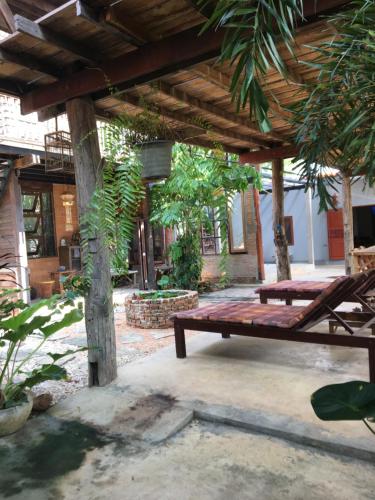 a wooden pergola with a bench in a courtyard at Baan Mali Lampang Homestay in Lampang