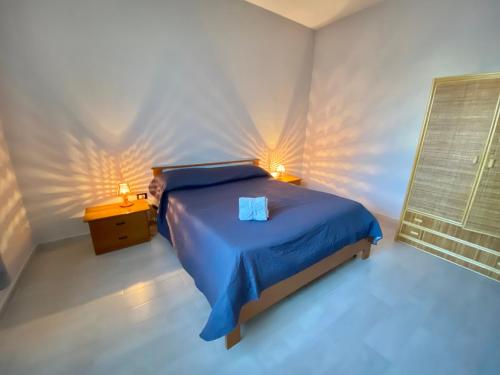 ein Schlafzimmer mit einem Bett mit blauer Bettwäsche und zwei Lampen in der Unterkunft Appartamento Kleos Balestrate in Balestrate