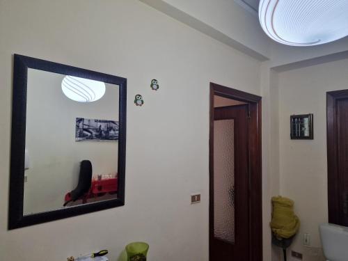 a mirror on a wall with a red chair in a bathroom at B&B da Giovy in Marsala