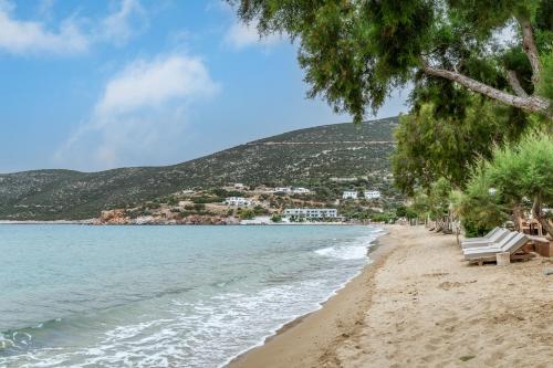 a beach with two white benches and the water at Cyclades Beach 3 in Sifnos
