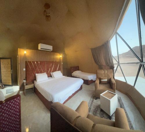 a bedroom with a bed and a large window at Golden Gate Luxury Camp in Wadi Rum