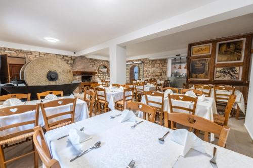 a restaurant with white tables and wooden chairs at Hotel Maslina in Seget