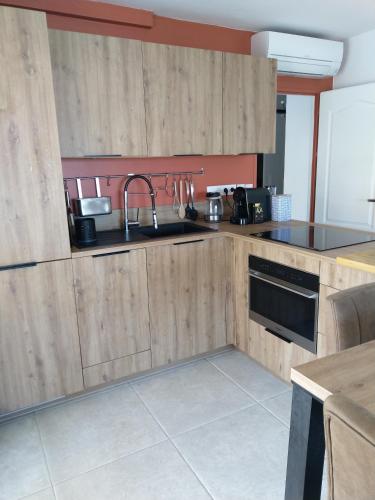 une cuisine avec des armoires en bois, un évier et une cuisinière dans l'établissement Appartement 40 m2 Vue Mer, à Hyères