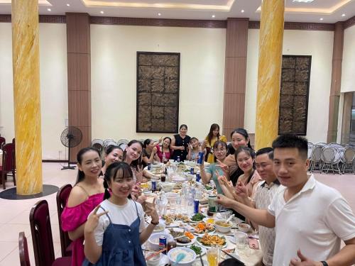 un grupo de personas sentadas alrededor de una larga mesa de cena en BIDV HOTEL CỬA LÒ, en Dong Quan