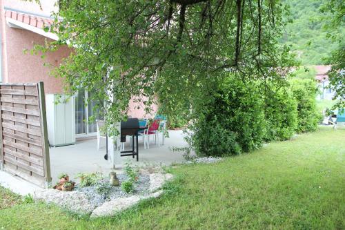 a garden with a table and chairs under a tree at Maison de Violette in Serrières-de-Briord