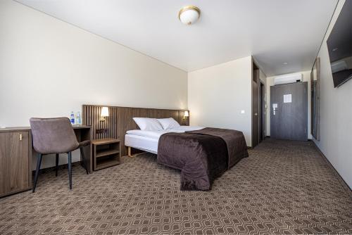a bedroom with a bed and a desk and a chair at Gradiali Wellness and SPA in Palanga