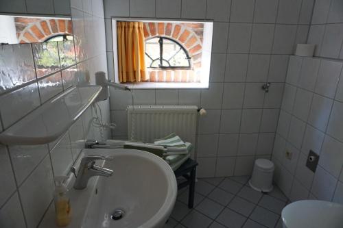 a white bathroom with a sink and a window at Beekenhof in Bommelsen