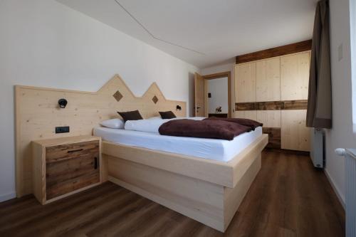 a bedroom with a large bed with a wooden headboard at Gasserhof in Campo di Trens