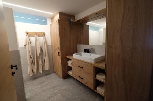 a bathroom with a white sink and a wooden cabinet at Gasserhof in Campo di Trens