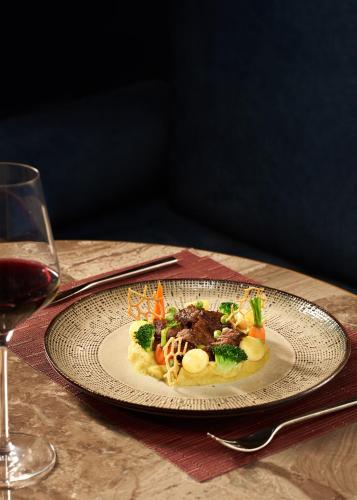 a plate of food on a table with a glass of wine at Mövenpick Hotel Hanoi Centre in Hanoi