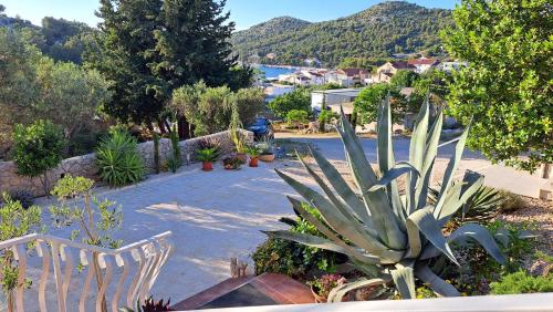 a garden with two white chairs and a plant at Apartmani Stipe in Drage