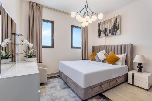 a white bedroom with a large bed and a chandelier at One Bedroom Apartment in Madinat Jumeirah Living by The S Holiday Homes in Dubai