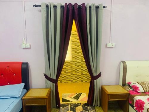 a room with curtains and a bed and two tables at Nabilah Homestay, Besut in Kampung Raja