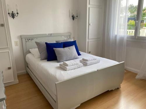 a white bed with blue and white pillows on it at Maison arcachonnaise proche plage - animaux acceptés in Lanton