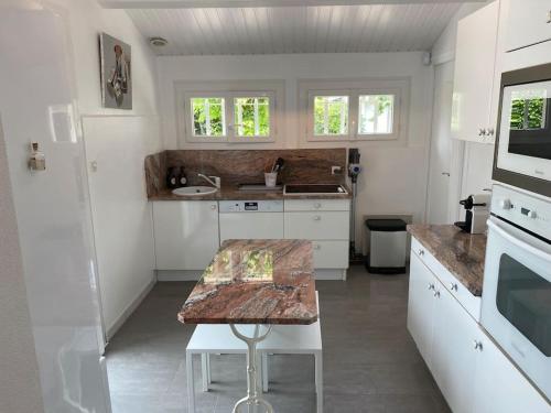a kitchen with white cabinets and a wooden table at Maison arcachonnaise proche plage - animaux acceptés in Lanton