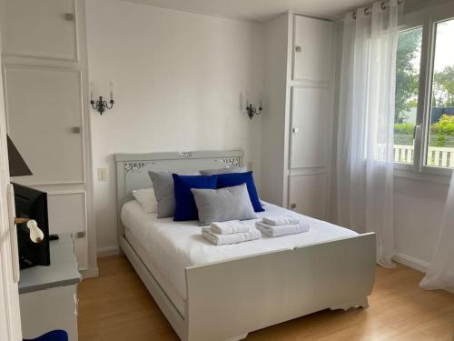 a white bedroom with a large white bed with blue pillows at Maison arcachonnaise proche plage - animaux acceptés in Lanton