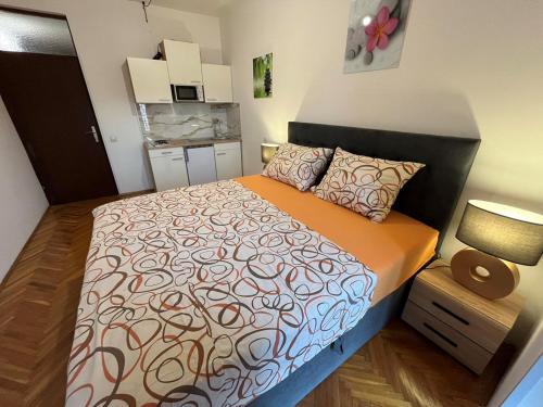 a bedroom with a bed with a orange and white comforter at APARTMENTS JADRANKa in Omišalj