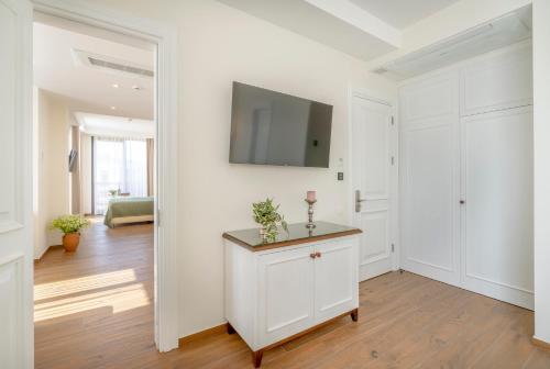 a white living room with a tv on a wall at Iris Hotel in Tbilisi City