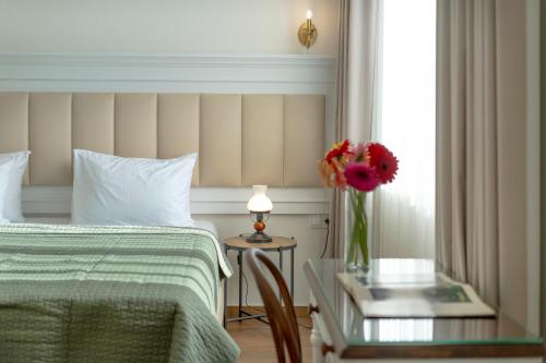 a bedroom with a bed and a table with a vase of flowers at Iris Hotel in Tbilisi City