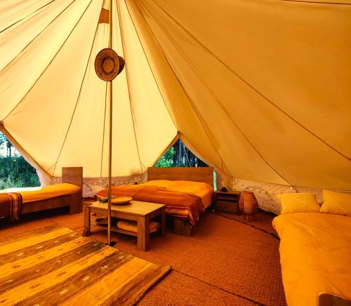 ein Zelt mit Betten und einem Tisch in einem Zimmer in der Unterkunft Under Canvas Bornholm in Østermarie