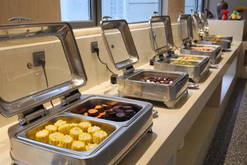 a row of trays of food on a buffet line at Ramada by Wyndham Wuhan Wangjiawan in Wuhan