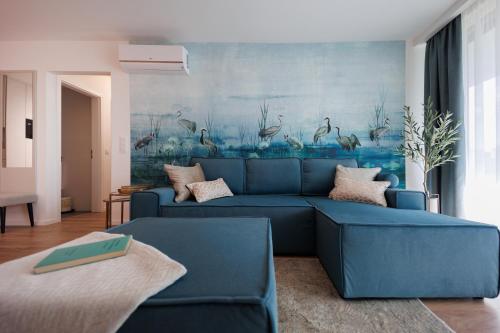a blue couch in a living room with a painting at Wave Luxury Apartment in Siófok