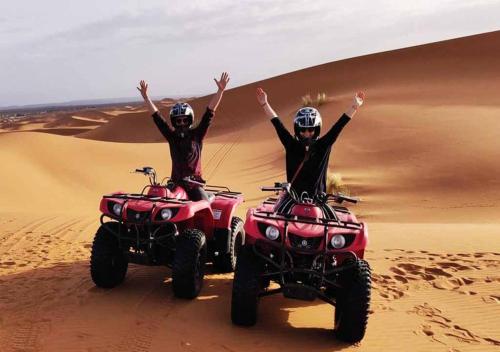 two people riding on atvs in the desert at Merzouga Lovely Luxury Camp in Merzouga