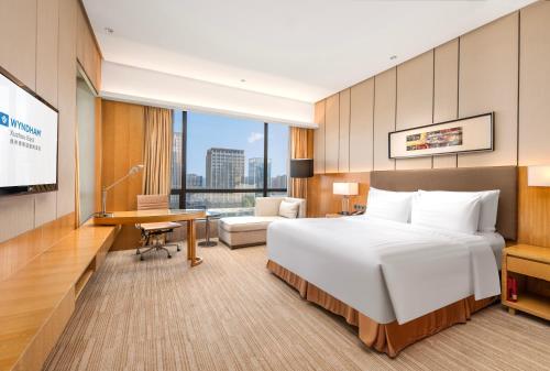 Habitación de hotel con cama grande y escritorio. en Wyndam Xuzhou East, en Xuzhou