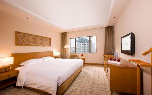 um quarto com uma grande cama branca e 2 janelas em Xi'an Dajing Castle Hotel em Xi'an