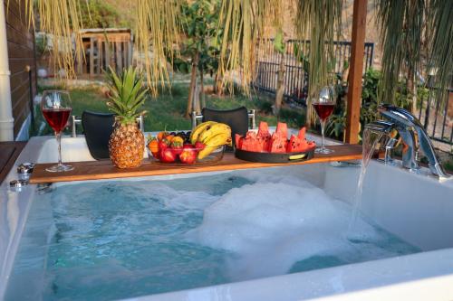 a bath tub with a tray of fruit and wine glasses at Koruwoodenhouse Alanya Gazipaşa in Gazipasa