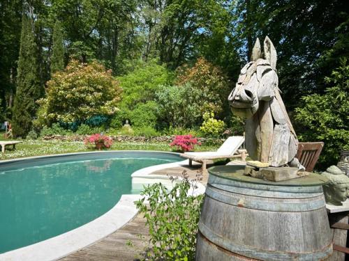 une statue d'un cheval debout à côté d'une piscine dans l'établissement GITES du BOIS des PERRUCHES, à Saint-Vincent-des-Bois